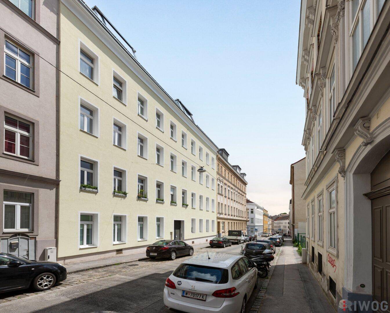 Ruhige Stadtstraße mit parkenden Autos und historischen Gebäuden.