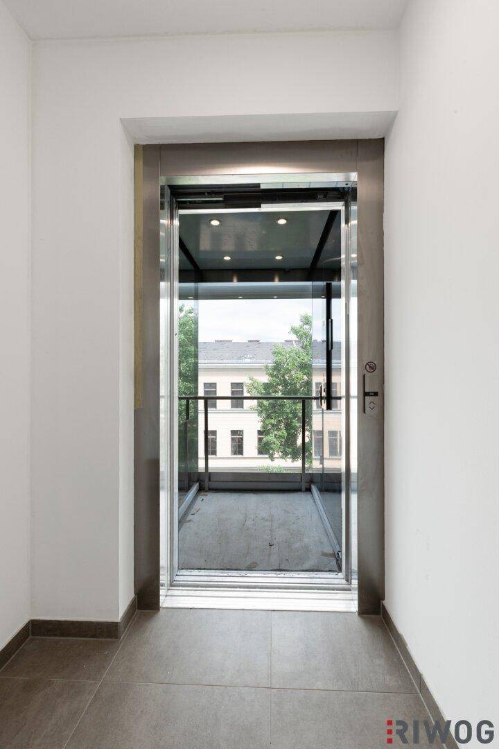 Moderner Glasaufzug im Gebäude, der einen Blick nach draußen ermöglicht.