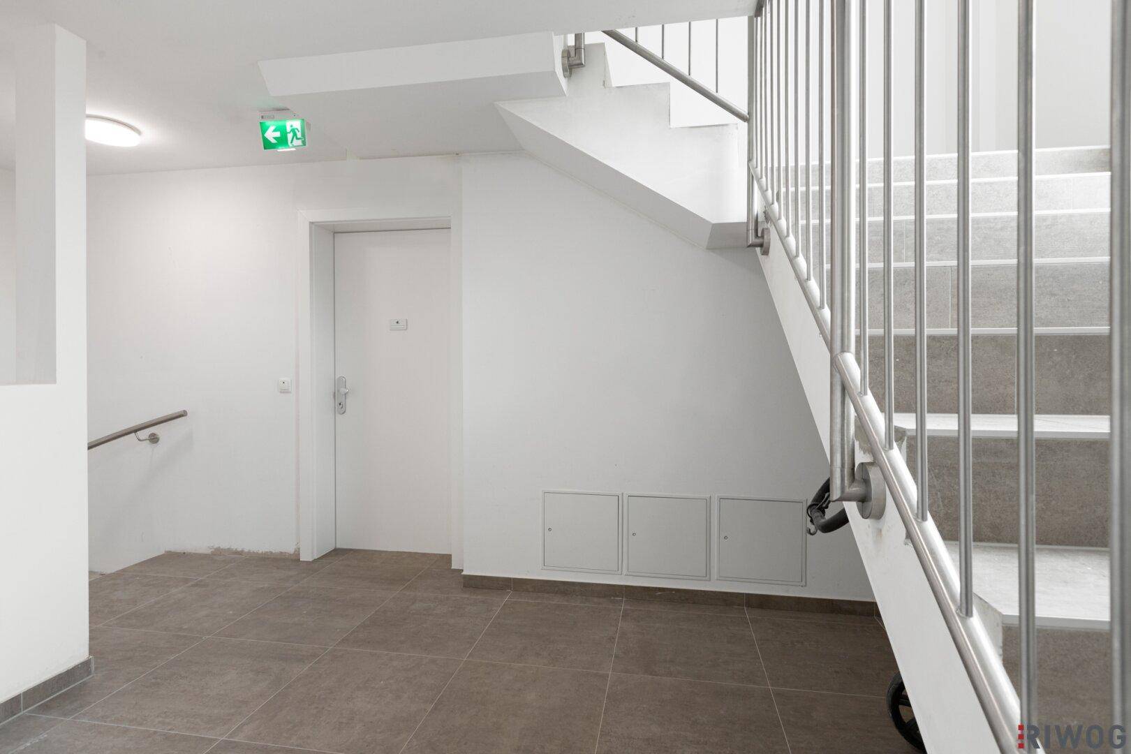 Heller Treppenaufgang im Gebäude mit Fliesenboden und Metallgeländer.
