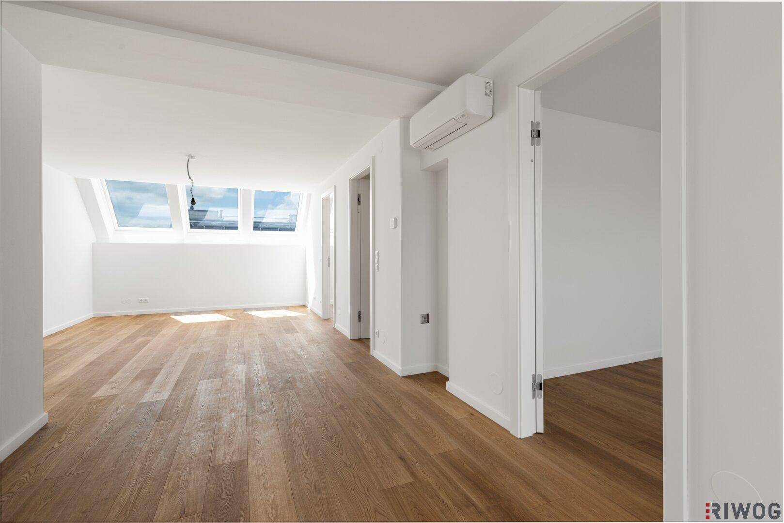 Geräumiger, heller Raum mit Holzboden, Dachfenstern und Klimaanlage.