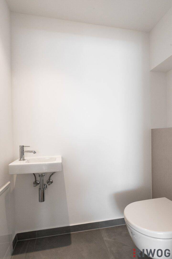 Modernes Gäste-WC mit wandhängendem Waschbecken und Toilette.