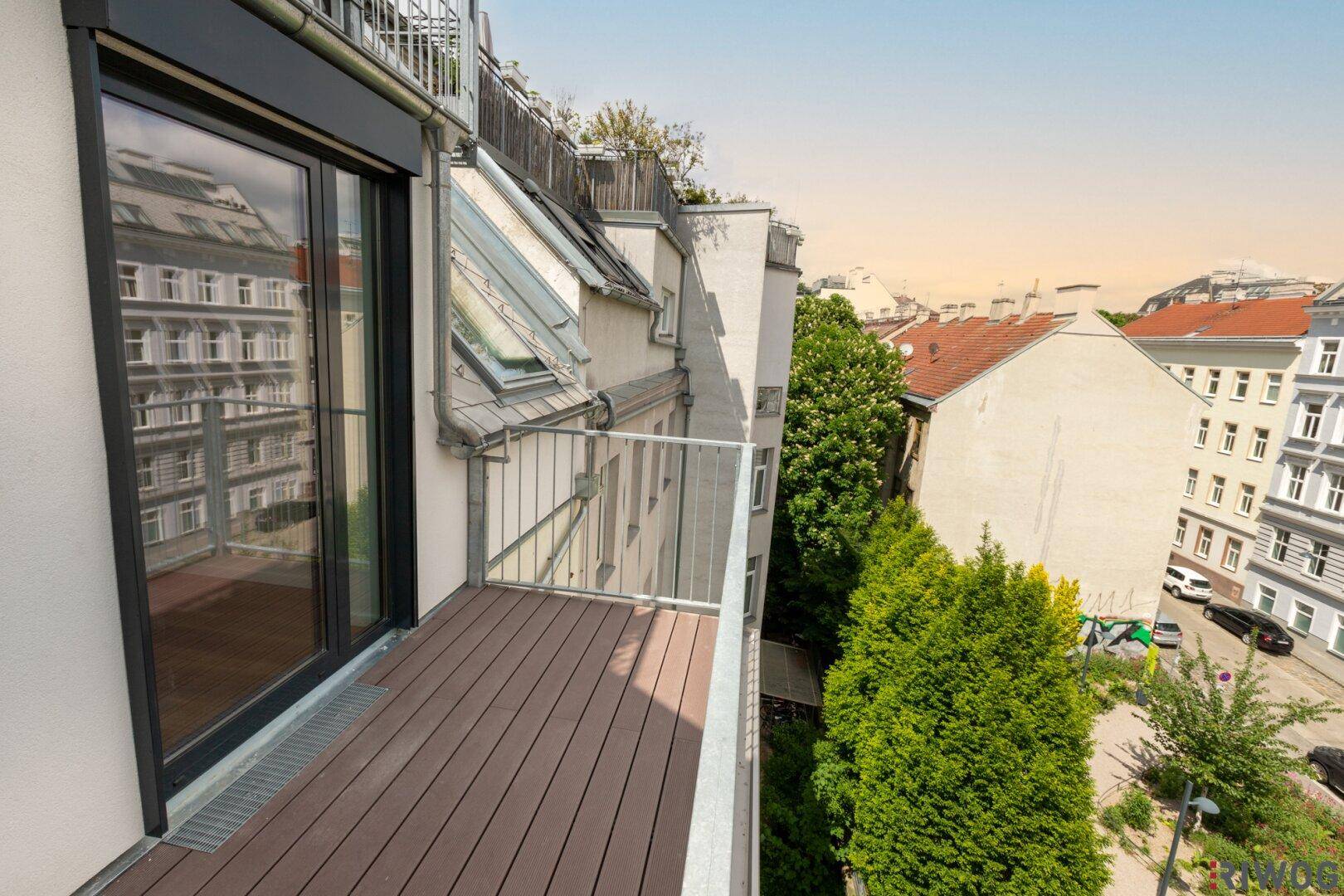 Balkon mit Holzdielen und Blick auf die Stadt und die Dächer der umliegenden Gebäude.