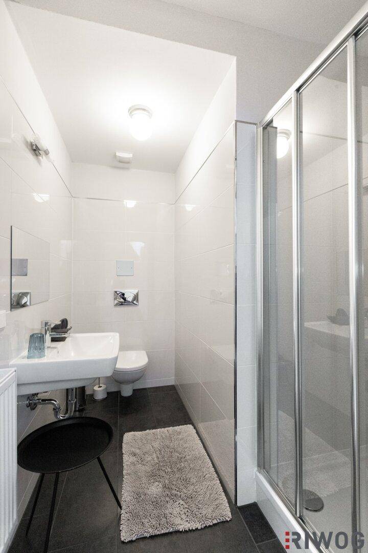 Kompaktes Badezimmer mit Dusche, Einzelwaschbecken und Wand-WC.