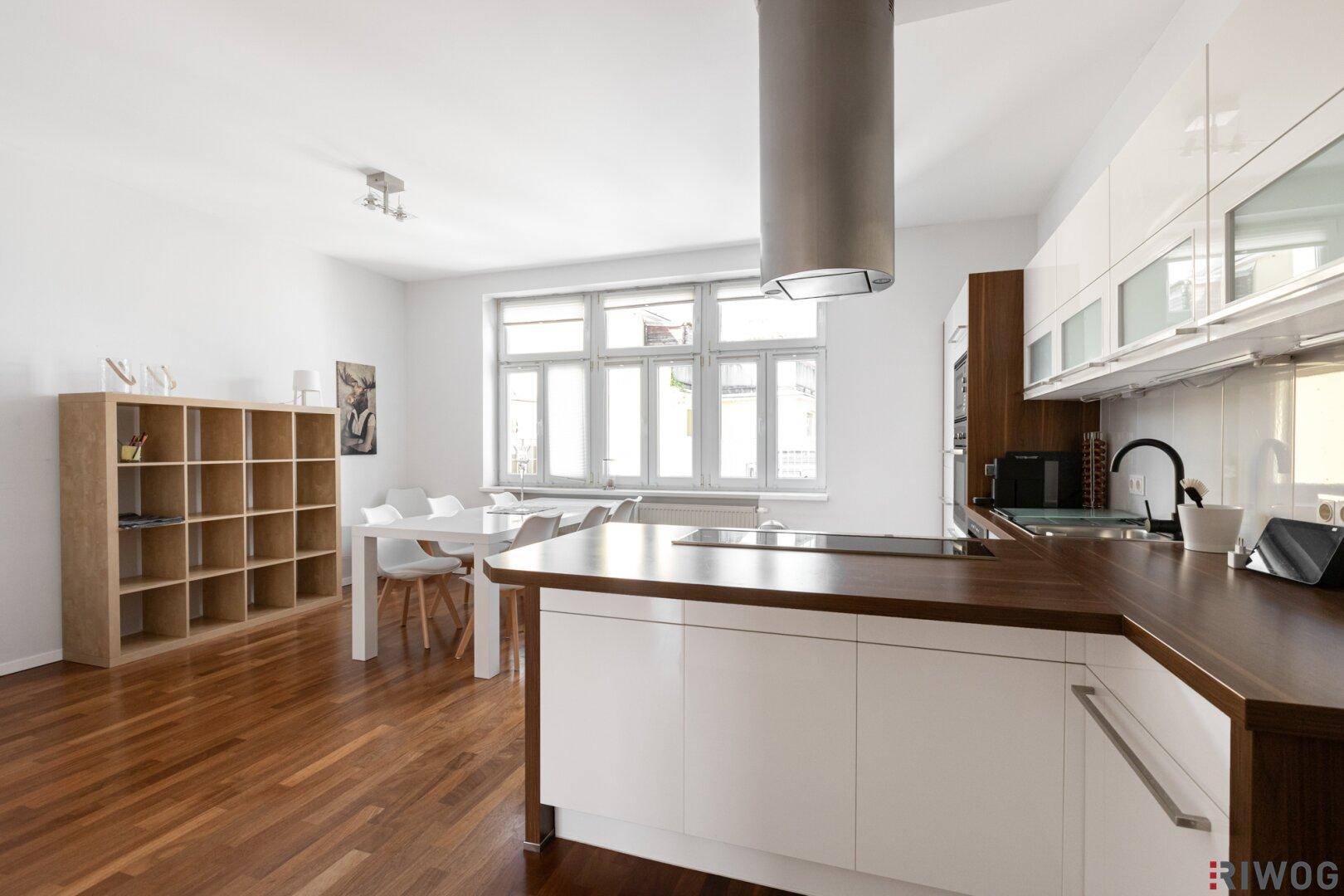 Moderne offene Küche mit Essbereich, Holzboden und großen Fenstern.