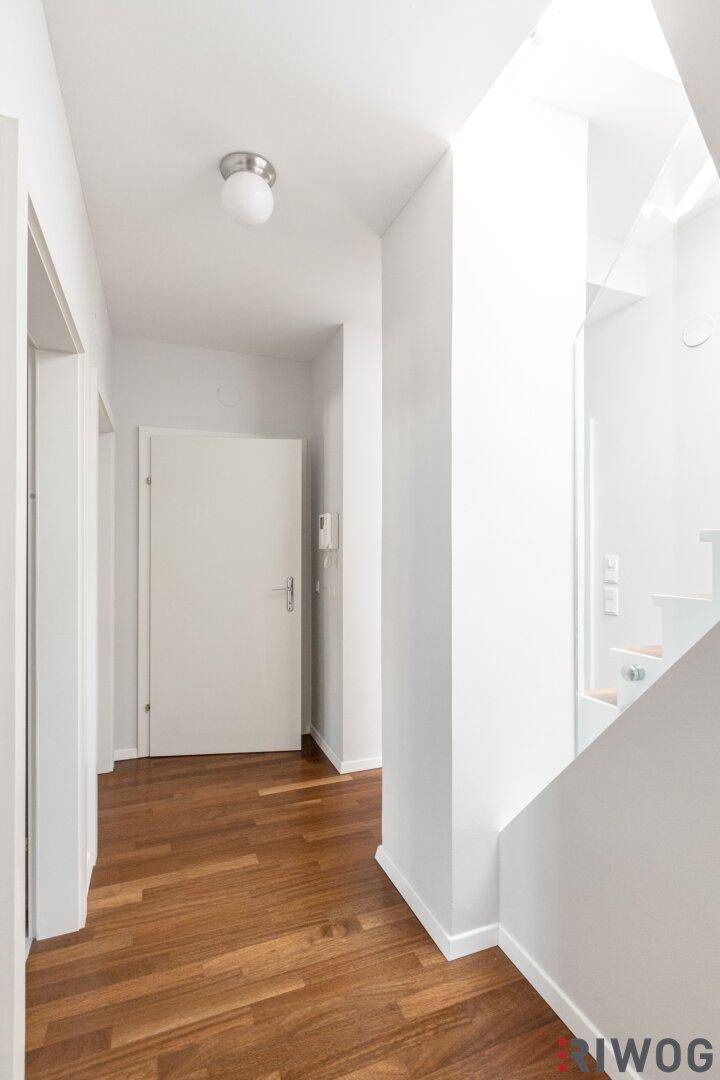 Heller Flur mit Holzboden und weißer Tür, die zu weiteren Räumen führt.