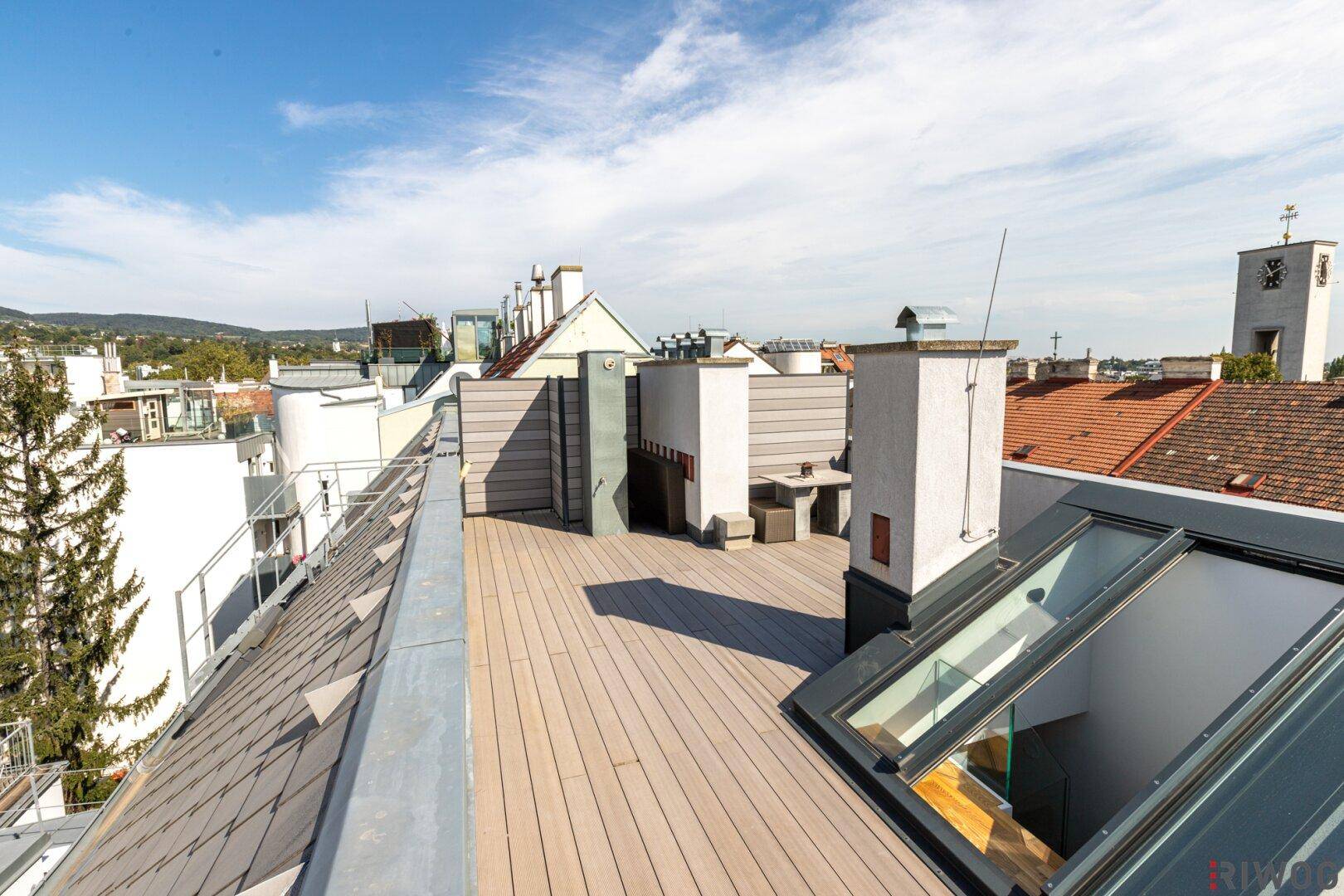 Weitläufige Dachterrasse mit Holzdeck und Panoramablick über die Stadt und die umliegenden Hügel.