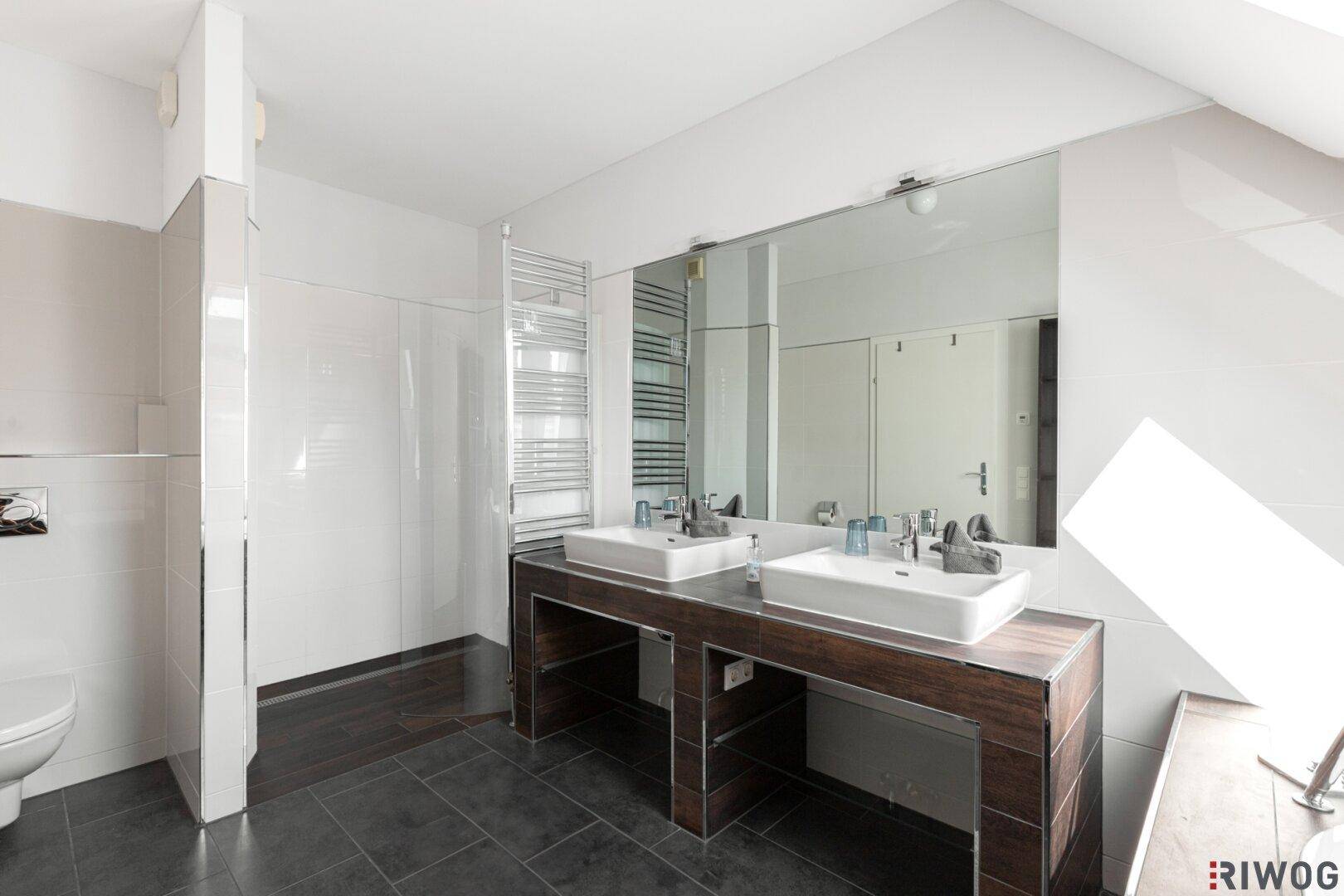 Modernes Badezimmer mit Doppelwaschbecken, Wand-WC und großem Spiegel.