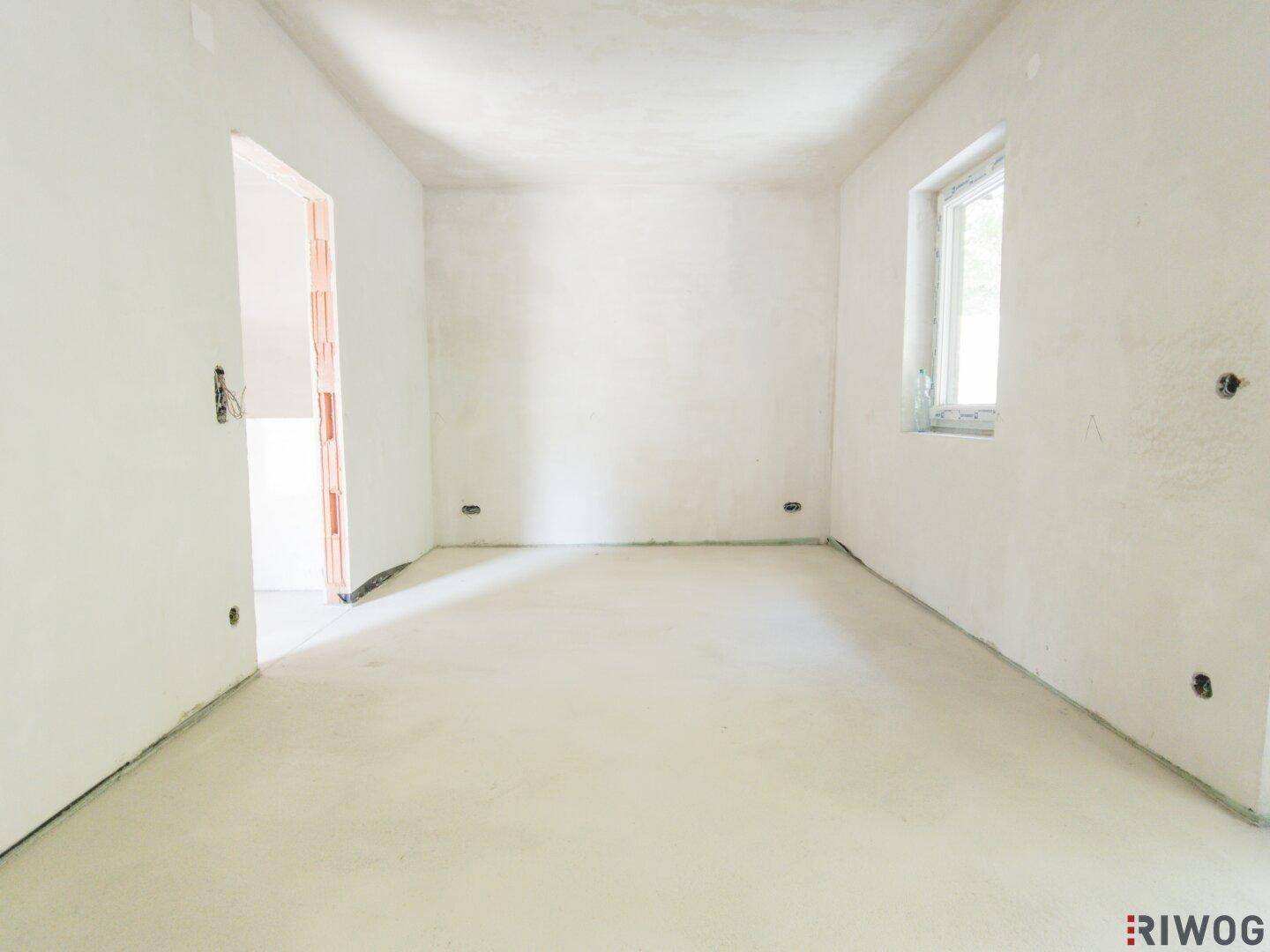 Helles, unfertiges Schlafzimmer mit einem Fenster, bereit für die individuelle Gestaltung.