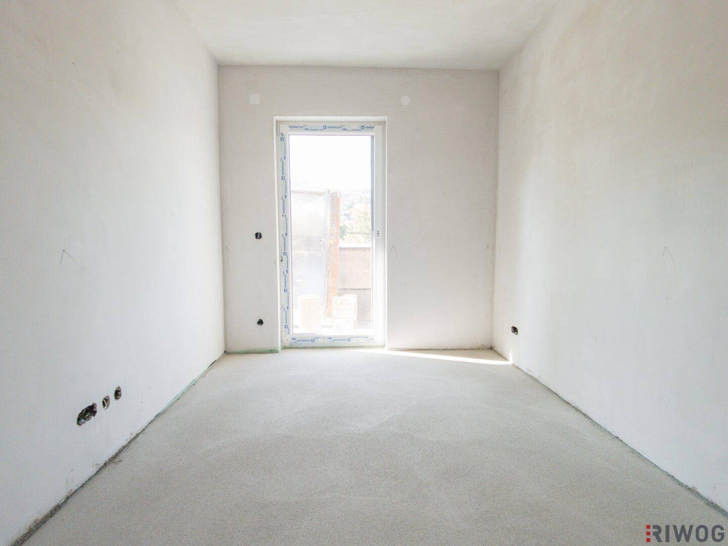 Heller, unfertiger Raum mit Balkonzugang, ideal für ein Schlafzimmer oder Arbeitszimmer.