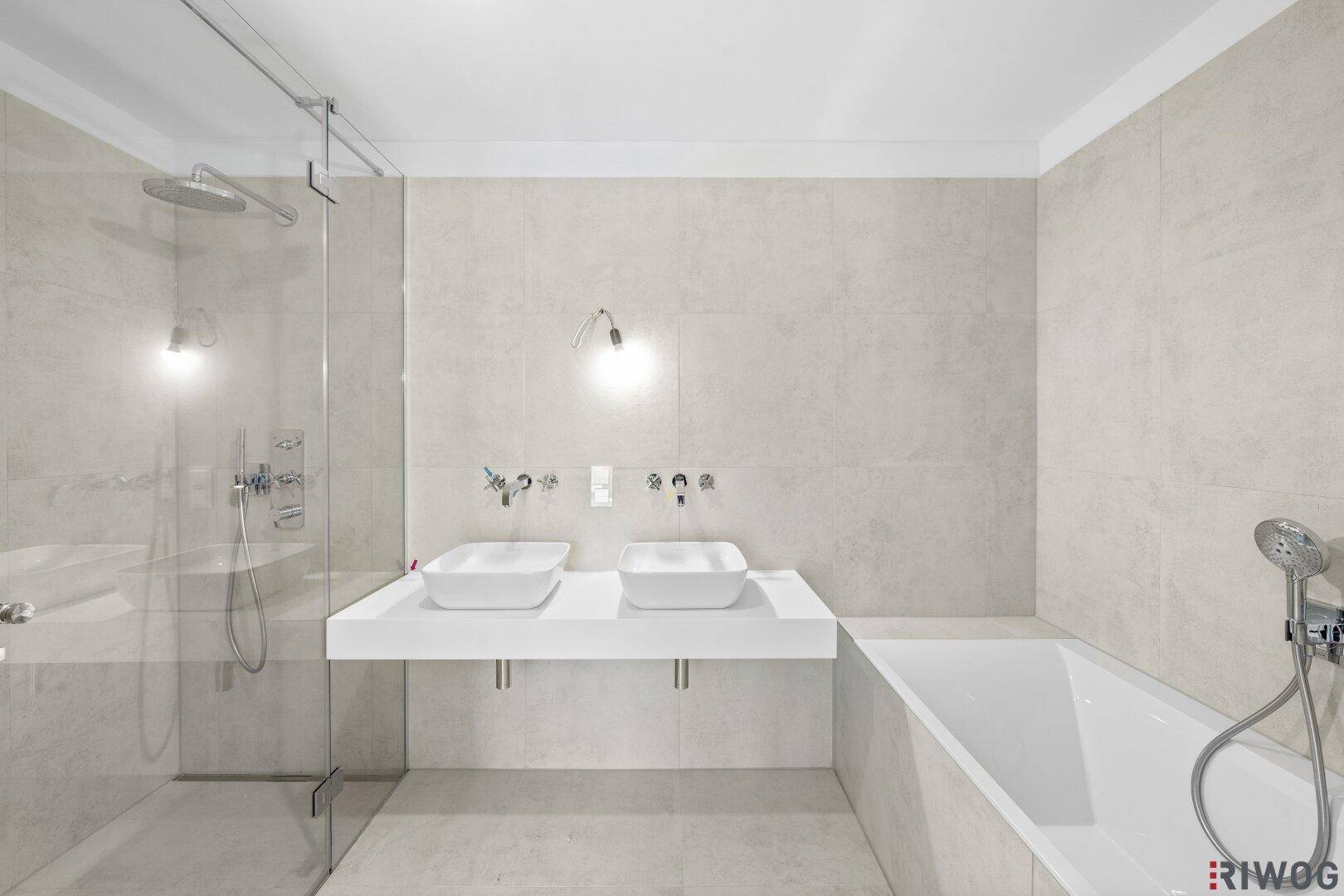 Modernes Badezimmer mit Doppelwaschbecken, Badewanne und begehbarer Dusche in hellen Fliesen.