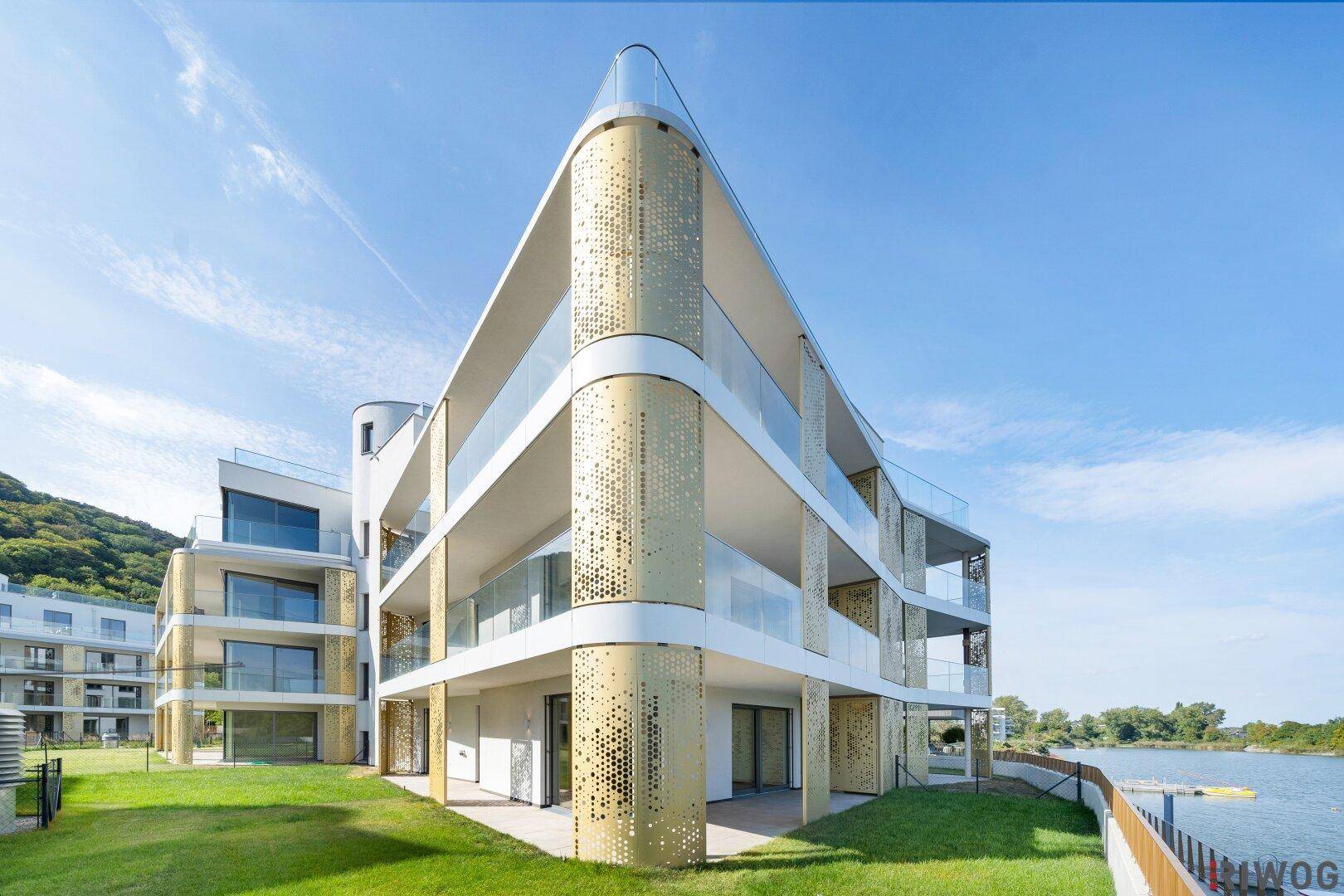 Elegantes Neubaugebäude mit moderner Architektur, Glasbalkonen und Blick auf den See.
