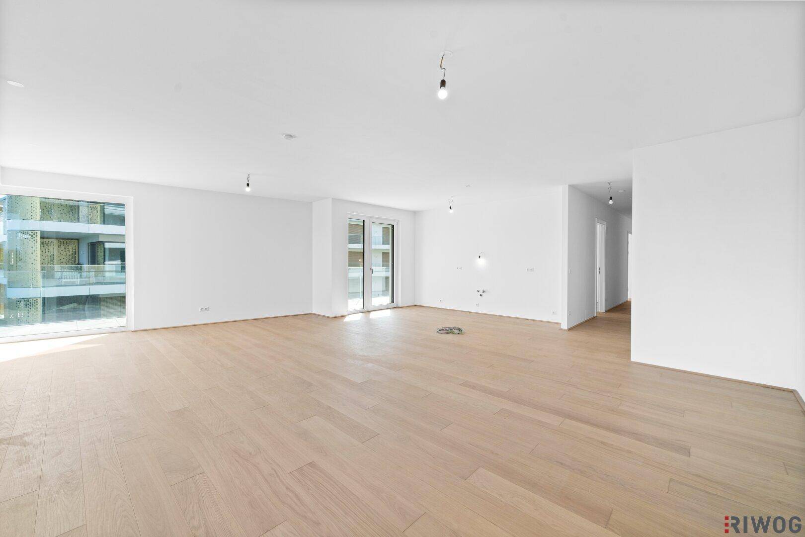 Geräumiger, heller Wohnbereich mit Holzboden und Zugang zu mehreren Balkonen.
