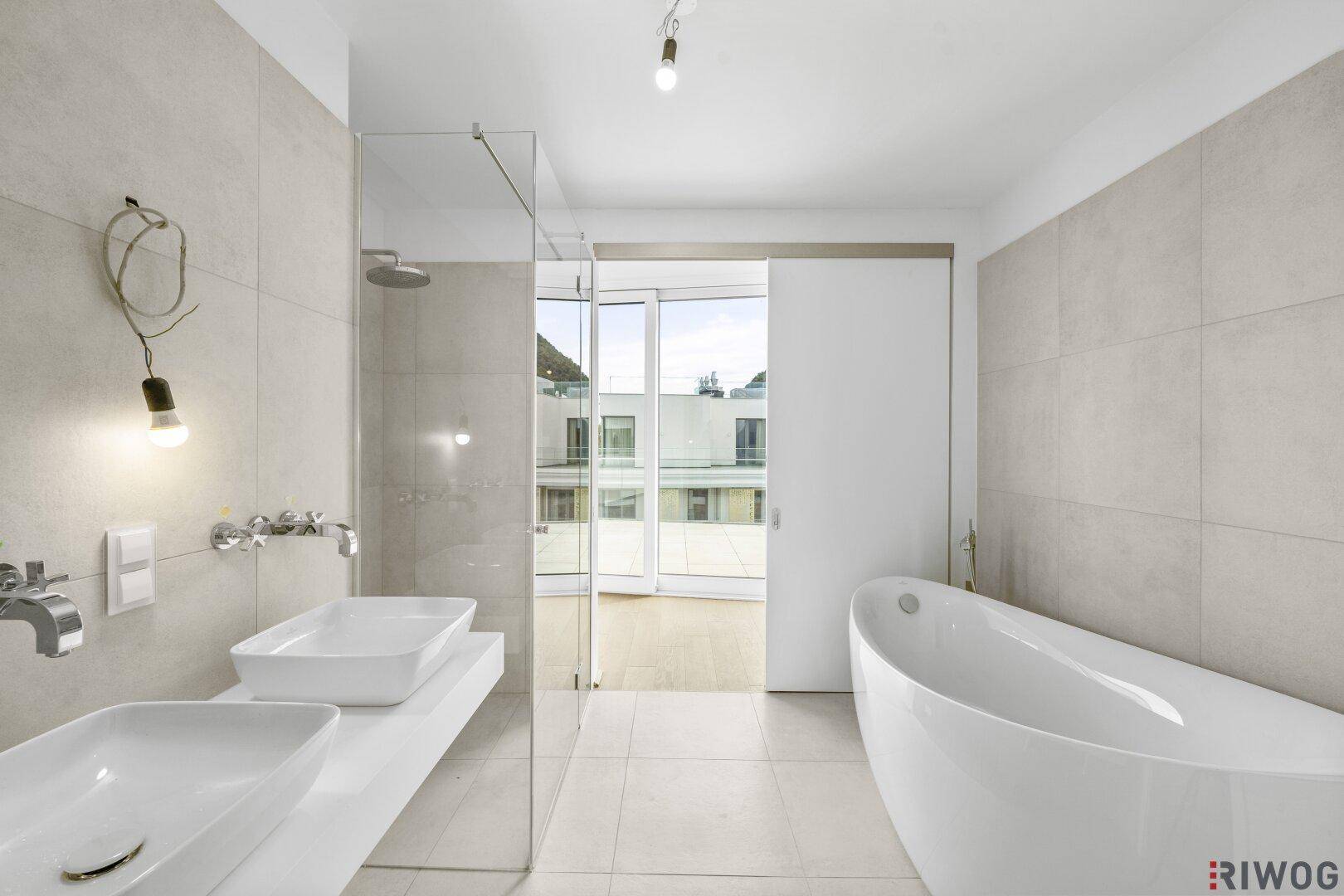 Modernes Badezimmer mit freistehender Badewanne, Doppelwaschbecken und Zugang zur Terrasse.