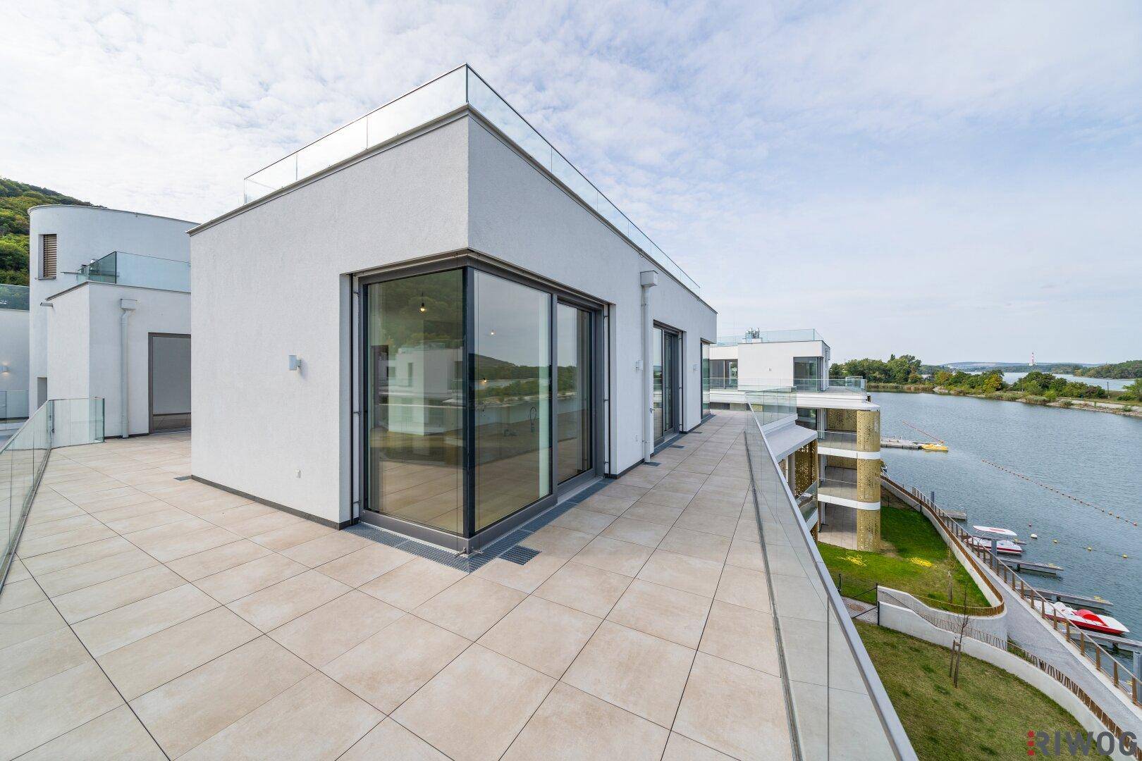 Große Dachterrasse mit moderner Architektur und Panoramablick auf das Wasser und die Umgebung.
