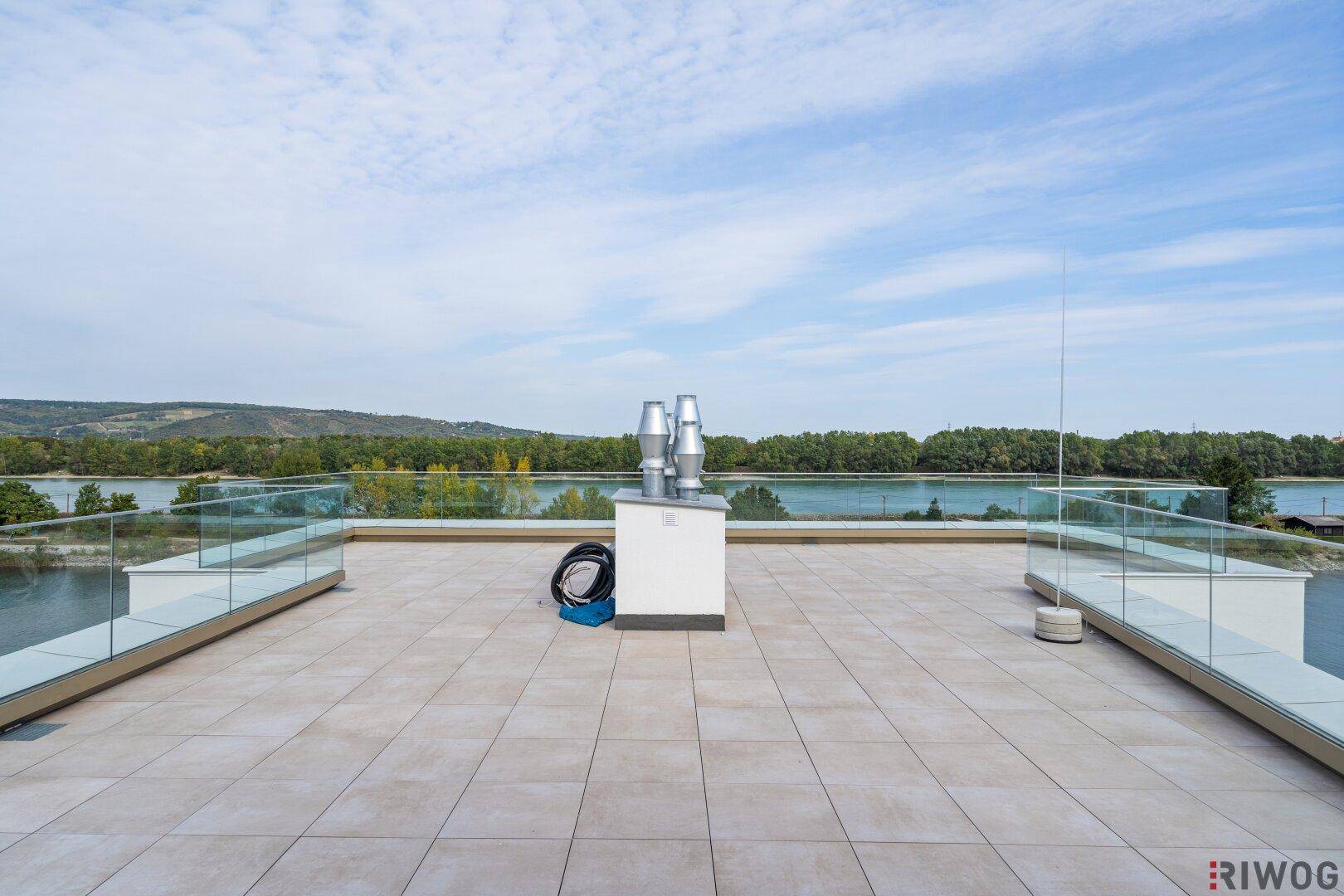 Weitläufige Dachterrasse mit Fliesenboden und Glasgeländer, ideal für Entspannung im Freien.