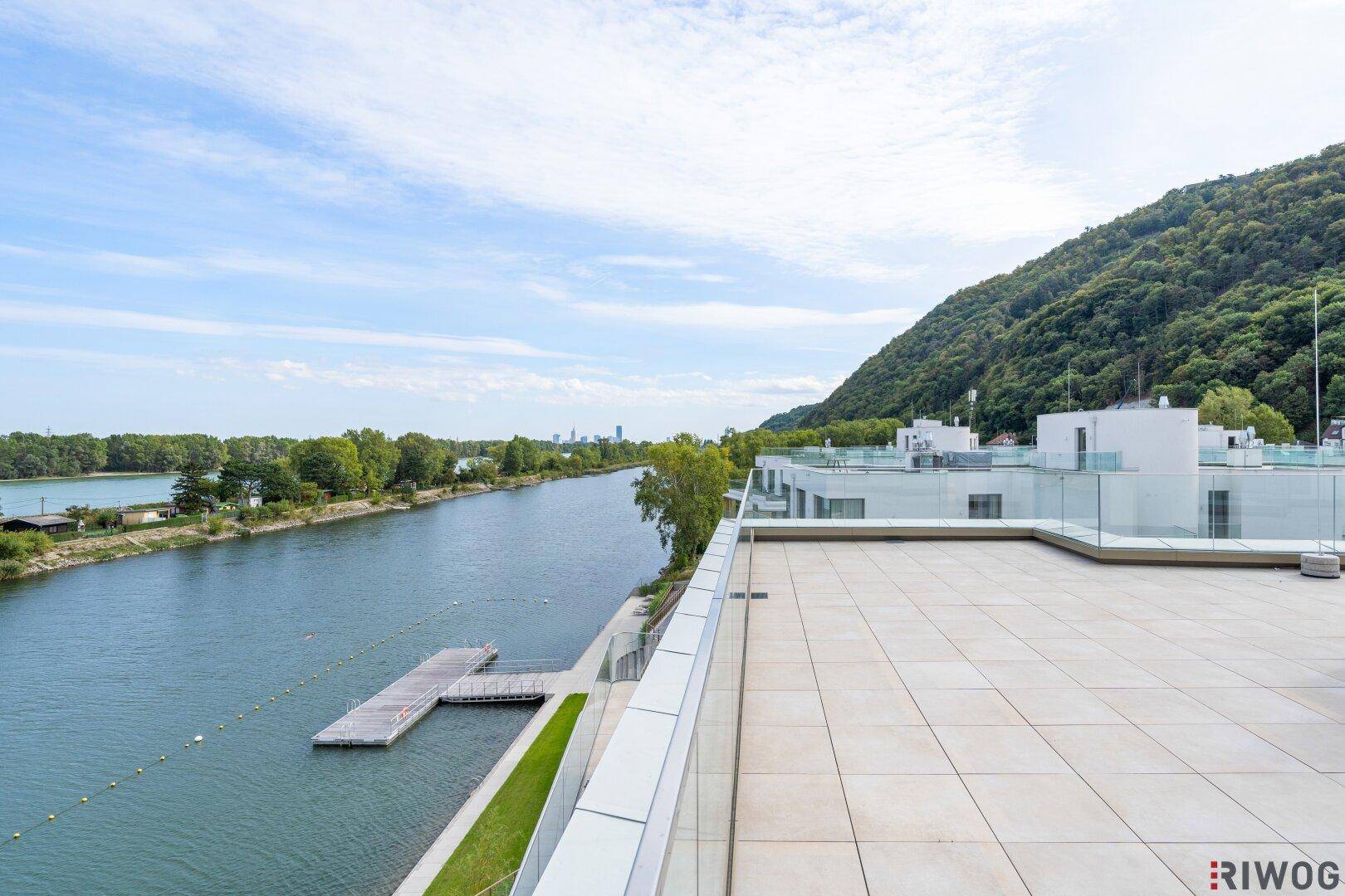 Geräumige Terrasse mit weitem Blick auf den Fluss und die bewaldeten Berge im Hintergrund.
