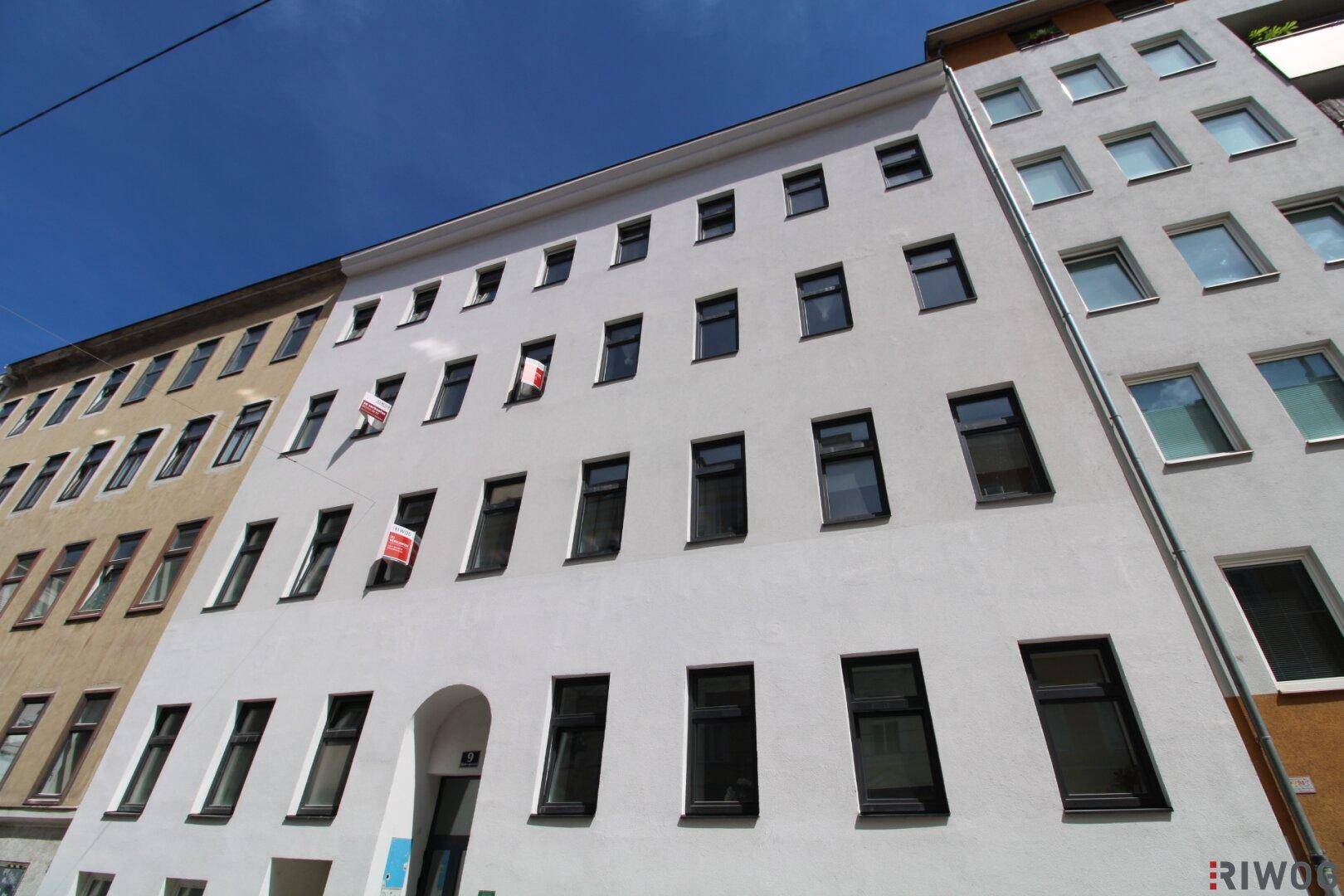 Fassade eines Mehrfamilienhauses mit zahlreichen Fenstern und moderner, frisch renovierter Optik.
