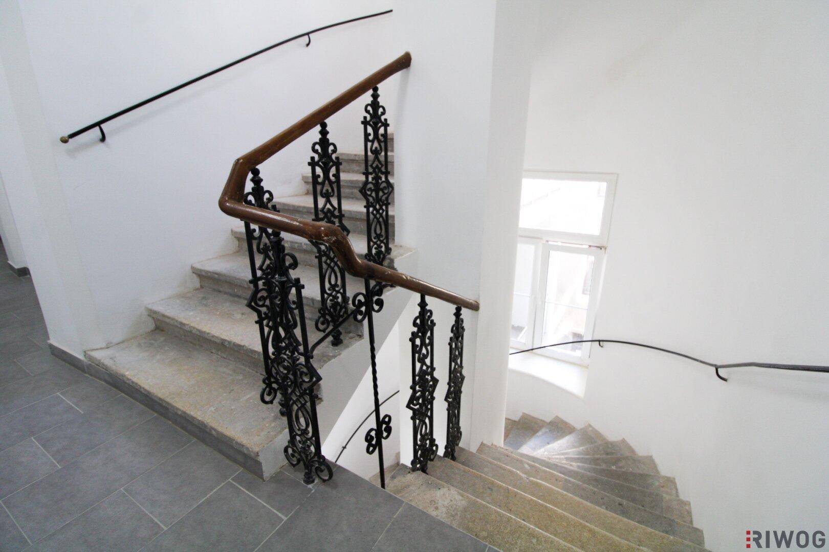 Historisches Treppenhaus mit kunstvollem schmiedeeisernem Geländer und Steinstufen, zeugt von altem Charme.