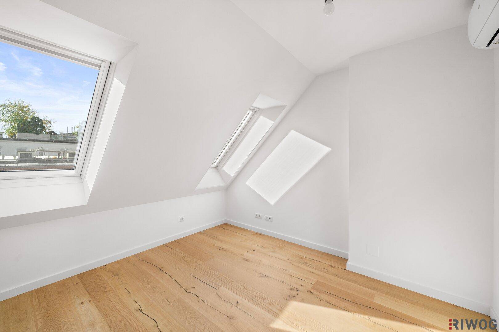 Geräumiges Schlafzimmer mit Holzboden, Dachfenstern und Klimaanlage für angenehmes Raumklima.