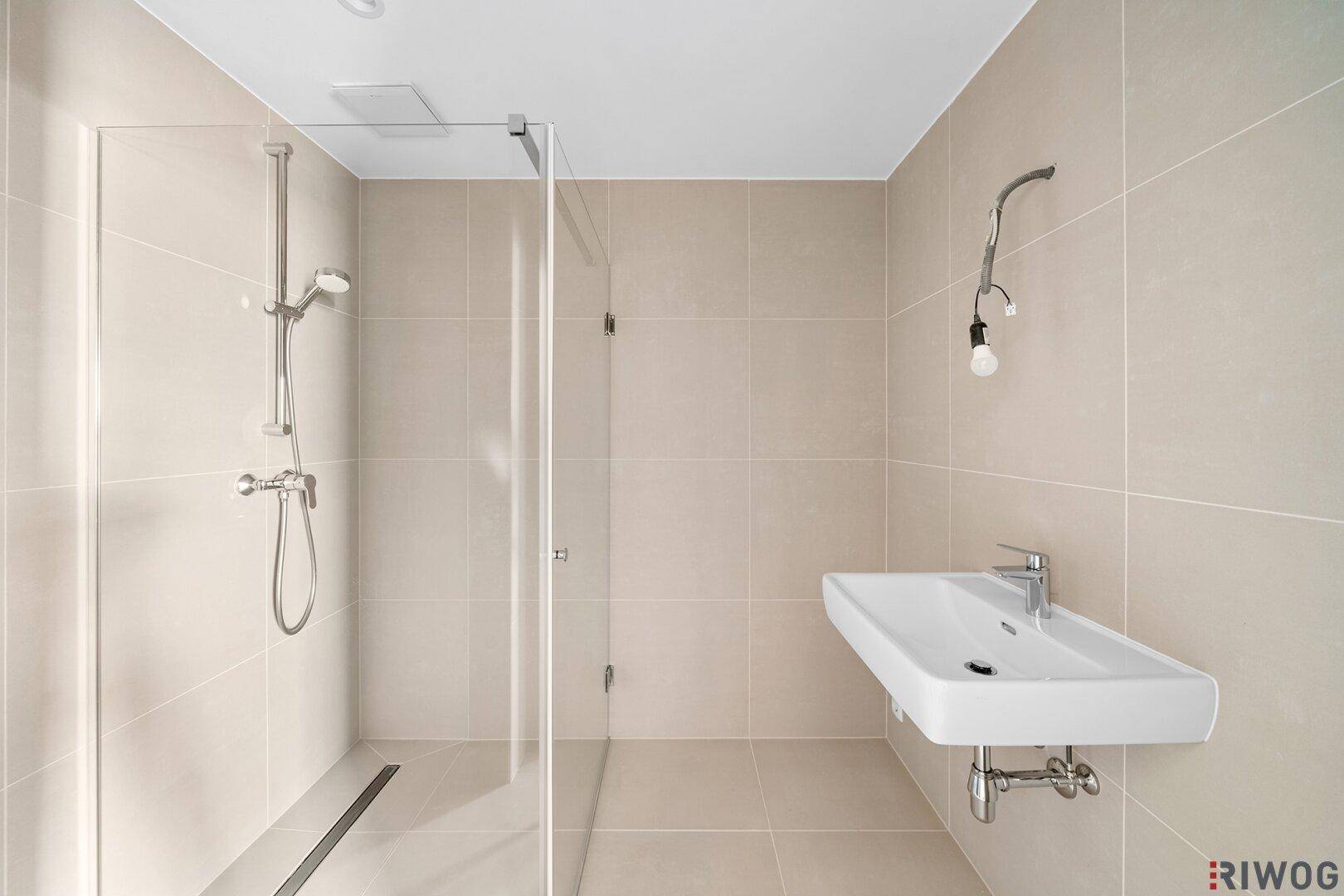 Modernes Badezimmer mit beigefarbenen Fliesen, ebenerdiger Dusche und einem schwebenden Wandwaschbecken.