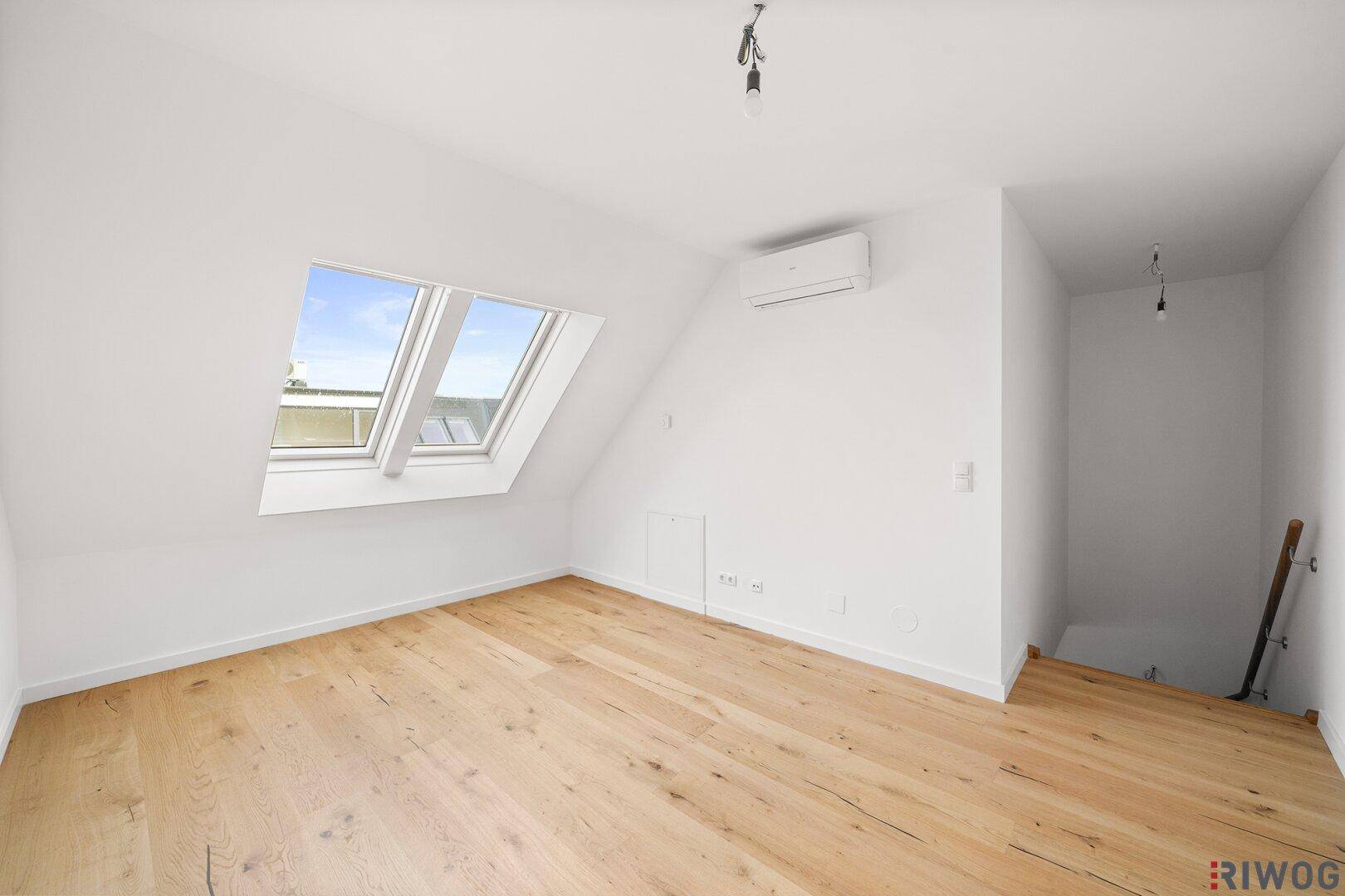 Helles Dachzimmer mit Holzboden, Dachfenstern und Klimaanlage, ideal als Schlafzimmer oder Büro.