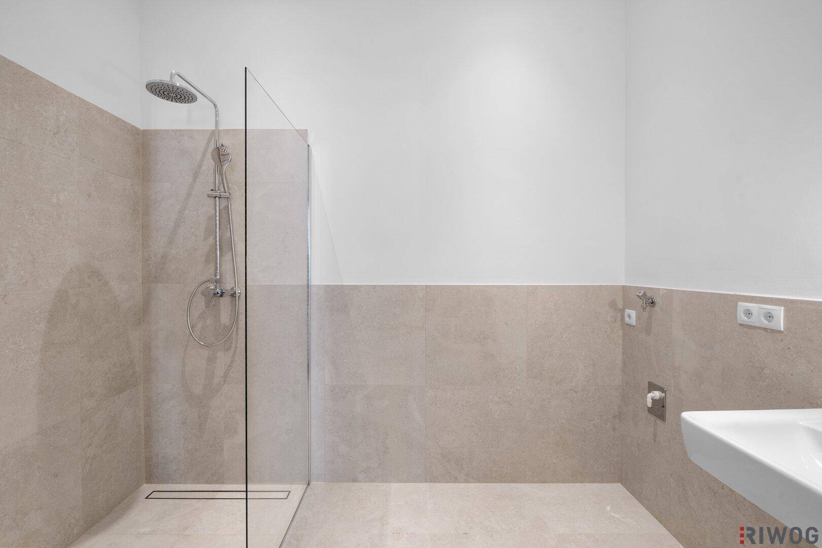 Modernes Badezimmer mit begehbarer Dusche, beigefarbenen Fliesen und minimalistischem Design.