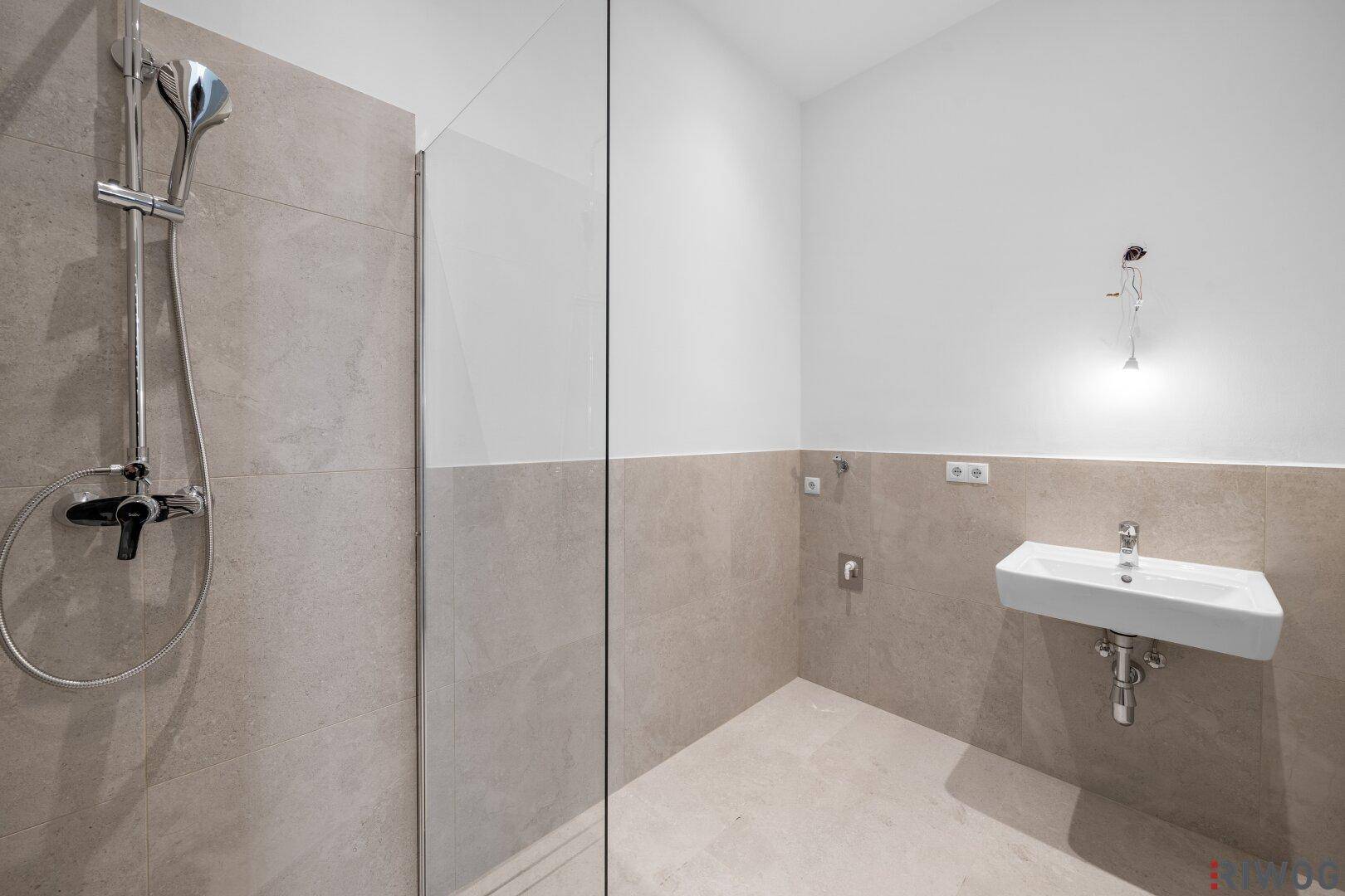 Zeitgemäßes Badezimmer mit großer begehbarer Dusche und modernem Waschbecken.