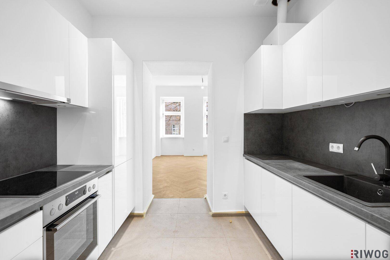 Neue, moderne Küche mit weißen Schränken und Blick in den angrenzenden Wohnbereich.