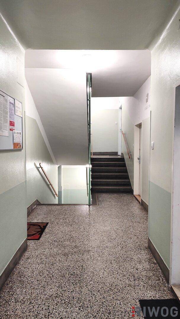 Heller Hausflur mit Treppenaufgang und Terrazzoboden in einem Mehrfamilienhaus mit klassischem Stil.