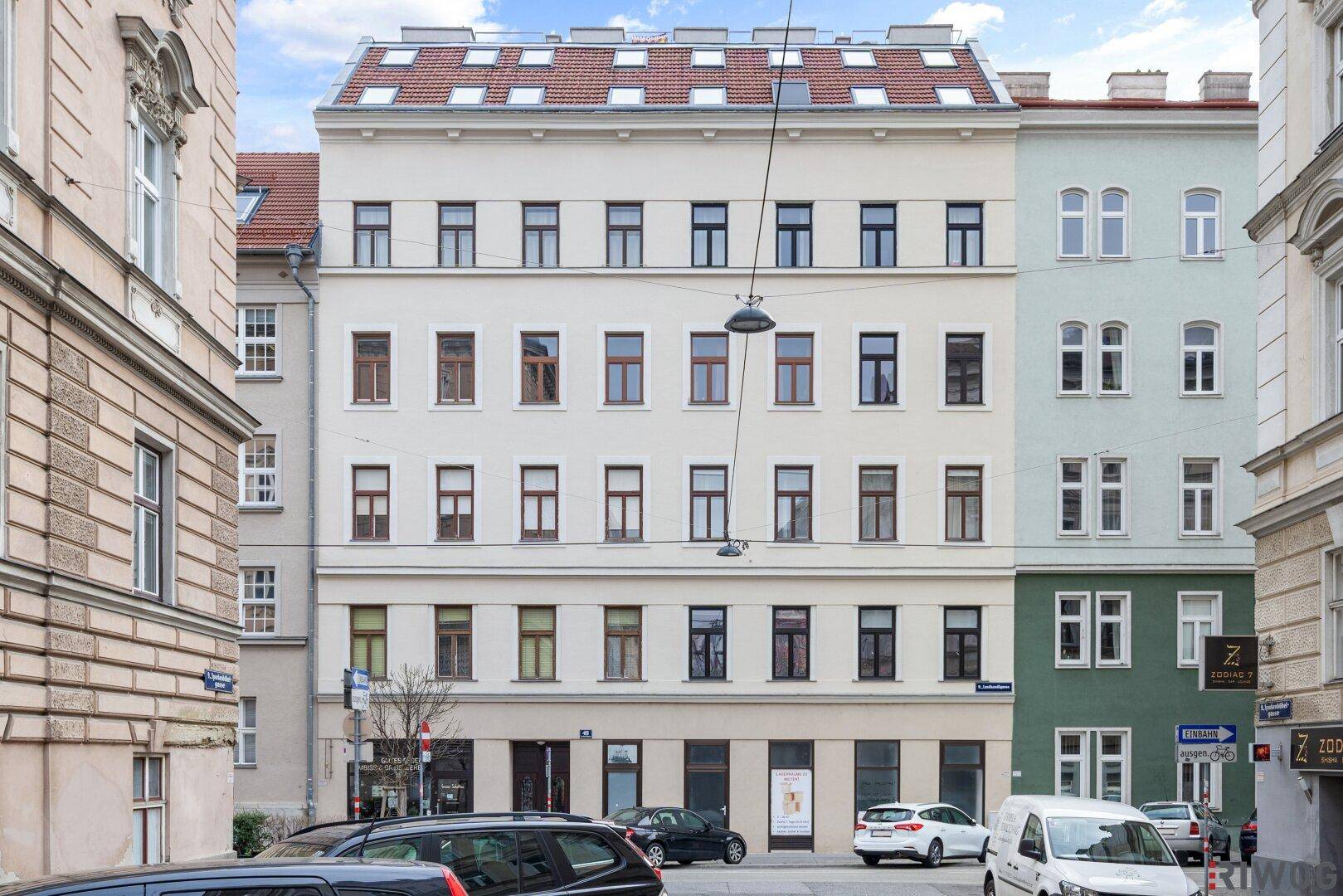 Klassische Fassade eines Mehrfamilienhauses mit vielen Fenstern und Mansarddach.