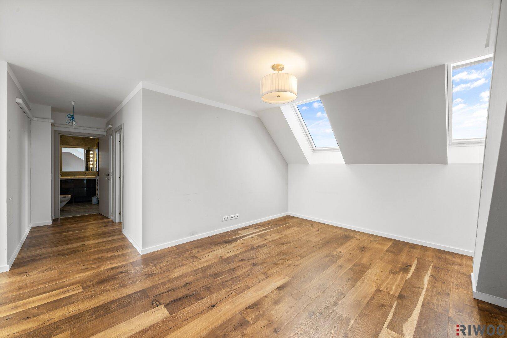 Helles Schlafzimmer mit Holzboden, Dachfenstern und viel natürlichem Licht.