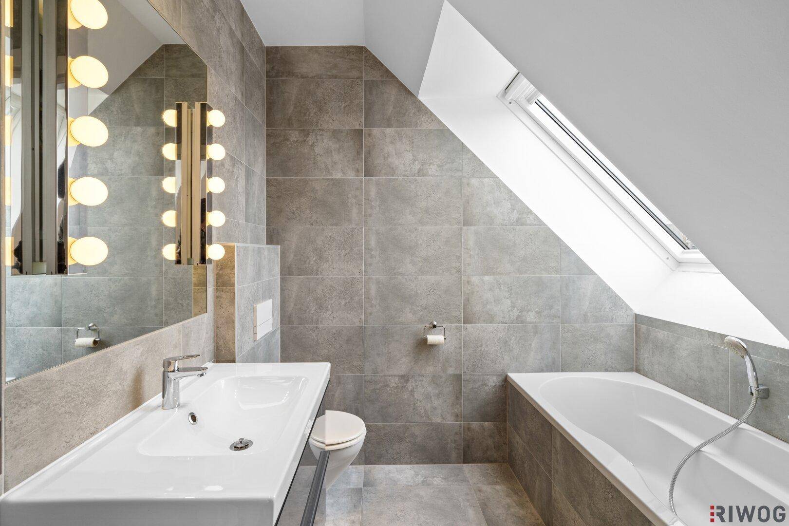 Modernes Badezimmer mit Badewanne, Einzelwaschbecken und Dachfenster.