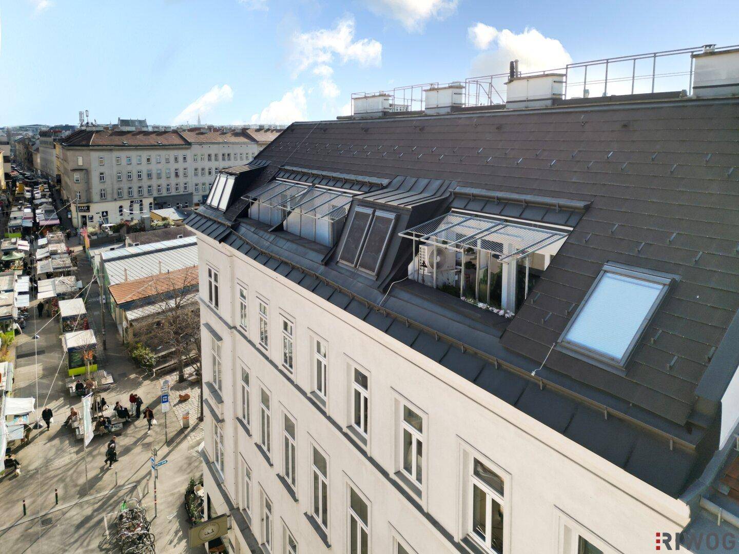 Nahaufnahme des Daches eines historischen Gebäudes mit modernen Dachfenstern und Gauben in urbaner Umgebung.