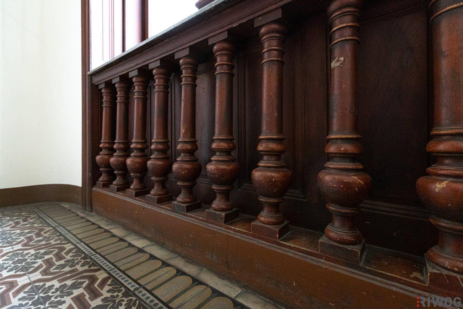 Historisches Holzgeländer mit gedrechselten Balustern, das den klassischen Stil des Gebäudes unterstreicht.