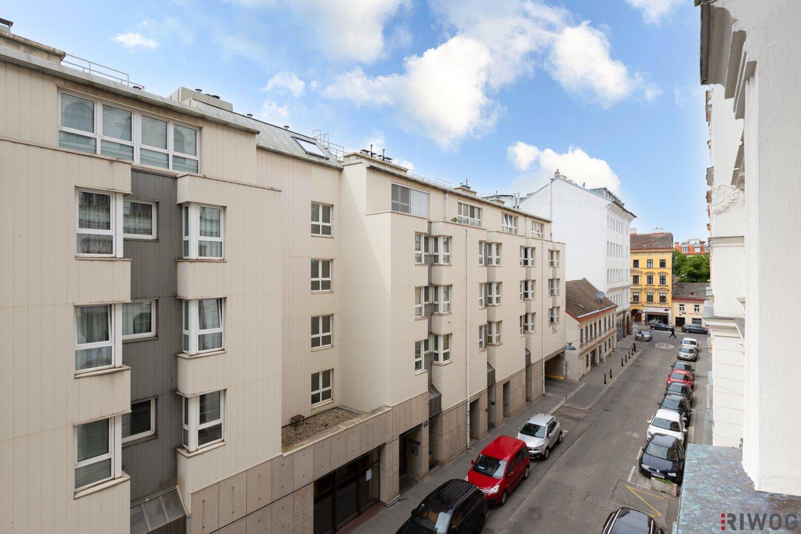 Weitläufiger Blick über die Straße und die angrenzenden Wohngebäude unter blauem Himmel.