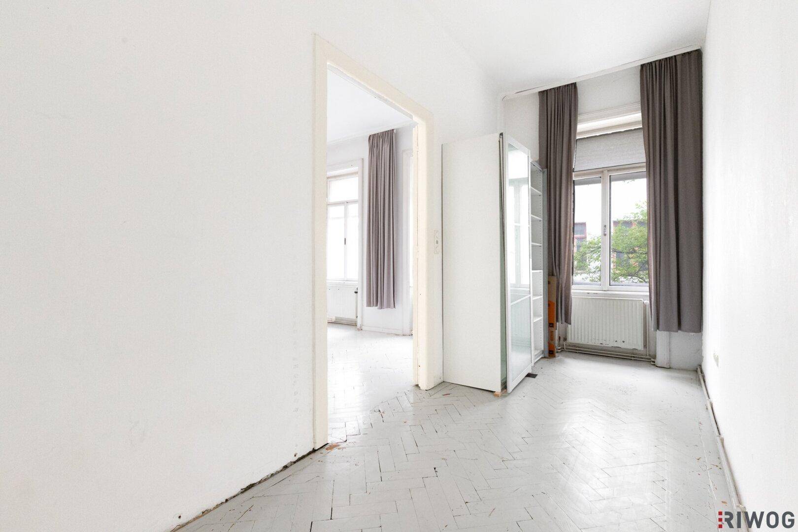 Heller Raum mit hohen Fenstern und Vorhängen, der viel natürliches Licht hereinlässt.