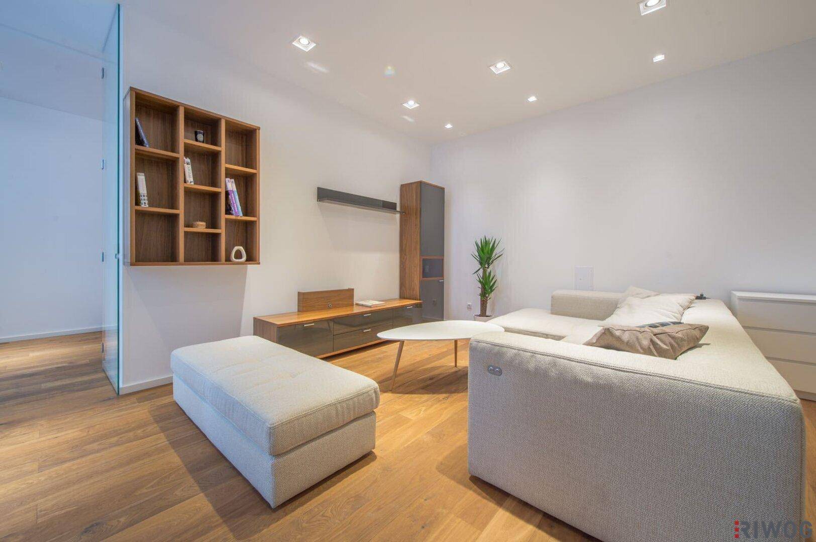 Moderner Wohnbereich mit Holzboden, bequemen Sofas und stilvollen Regalen an der Wand.