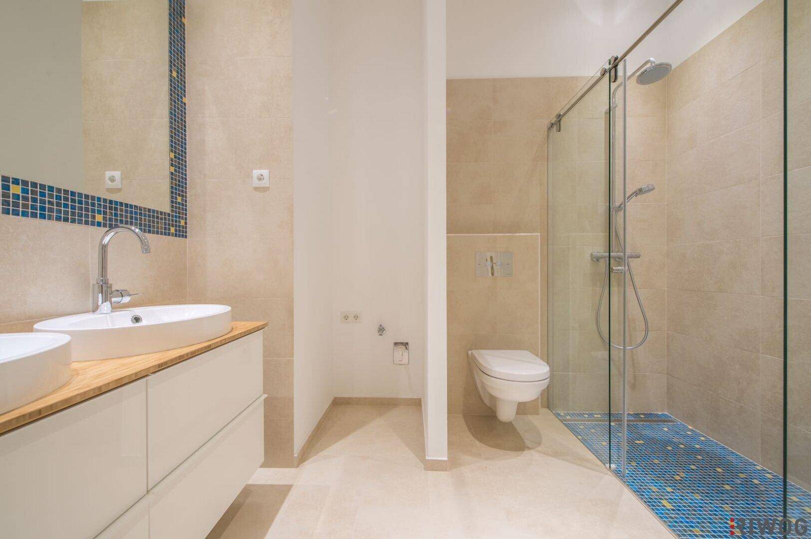 Elegantes Badezimmer mit Doppelwaschbecken, begehbarer Dusche und modernen Armaturen.