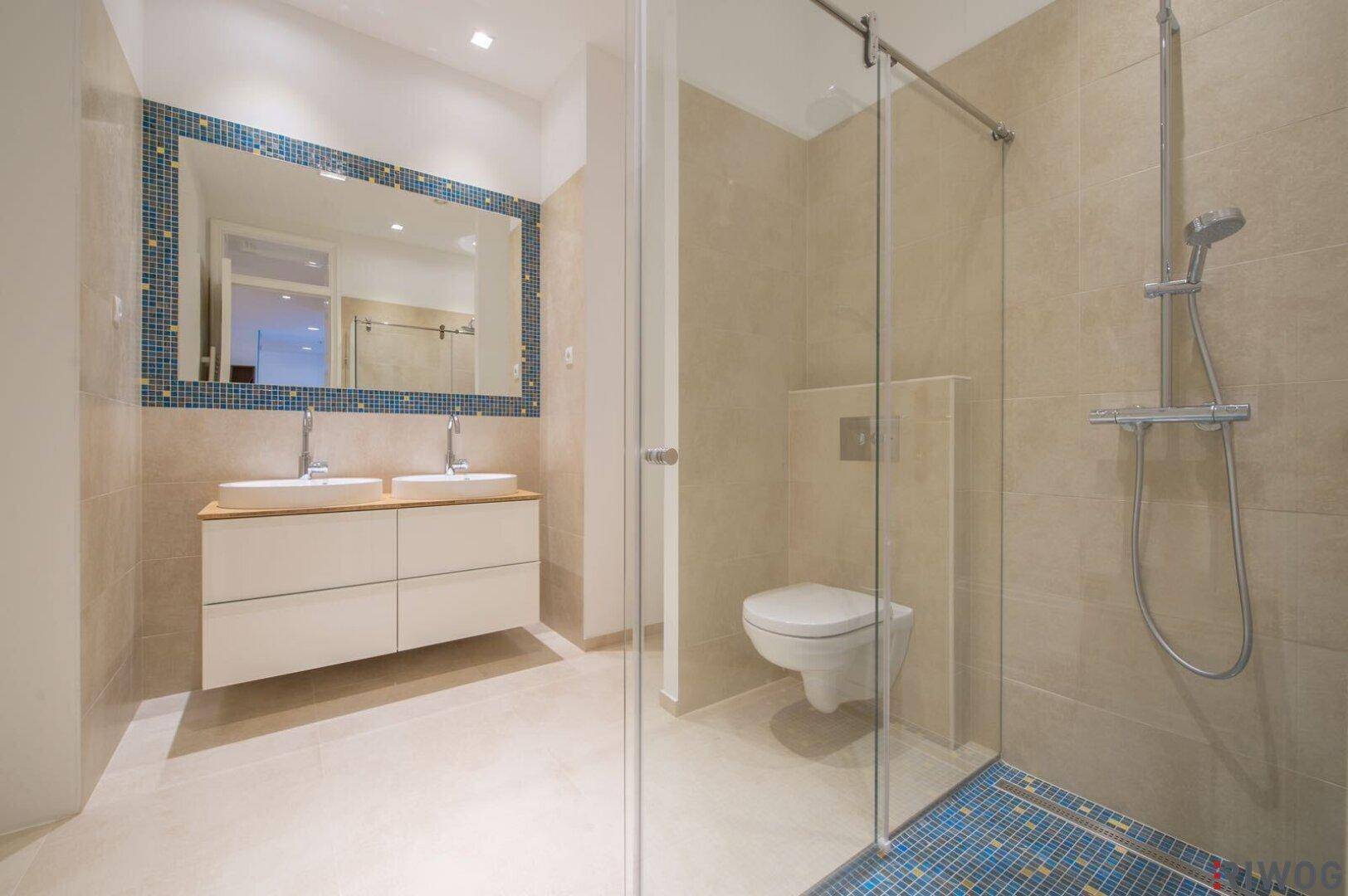 Modernes Badezimmer mit Doppelwaschbecken, begehbarer Dusche und stilvollen Mosaikfliesen.