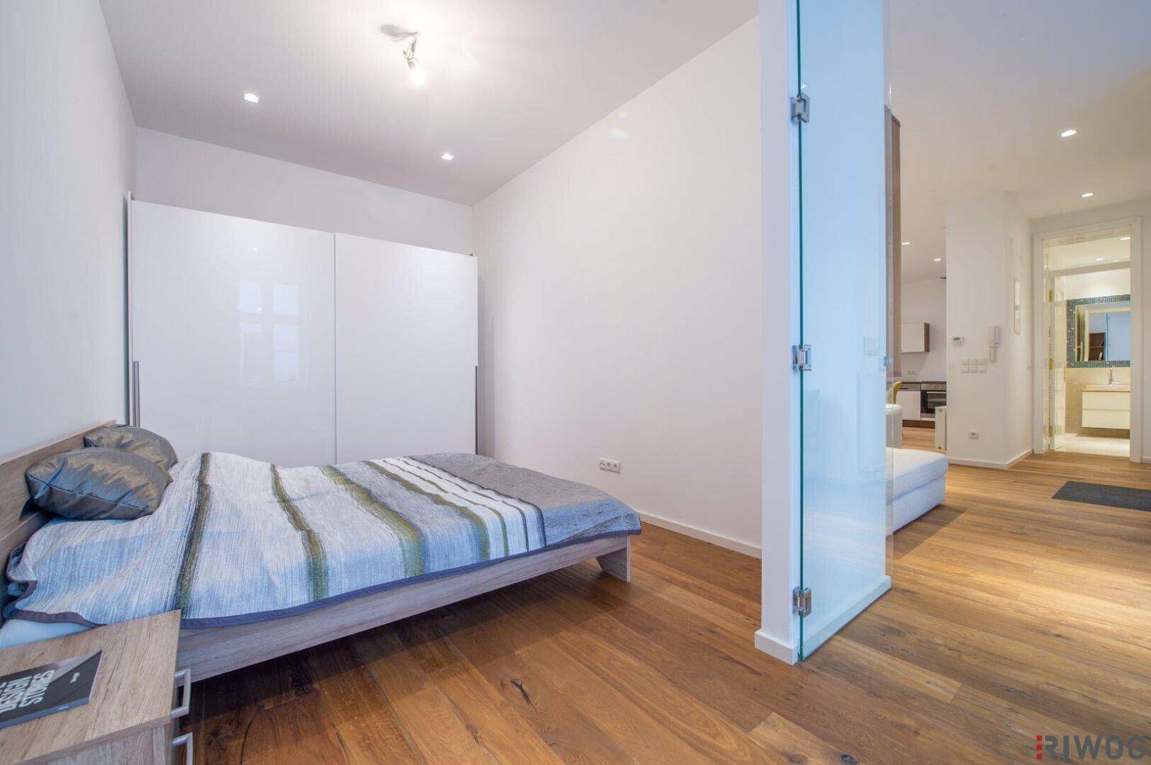 Modernes Schlafzimmer mit Holzboden, bequemen Bett und weißen Schränken, die viel Stauraum bieten.