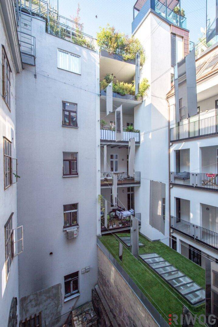 Innenhof eines modernen Gebäudes mit mehreren Balkonen und begrünten Terrassen.