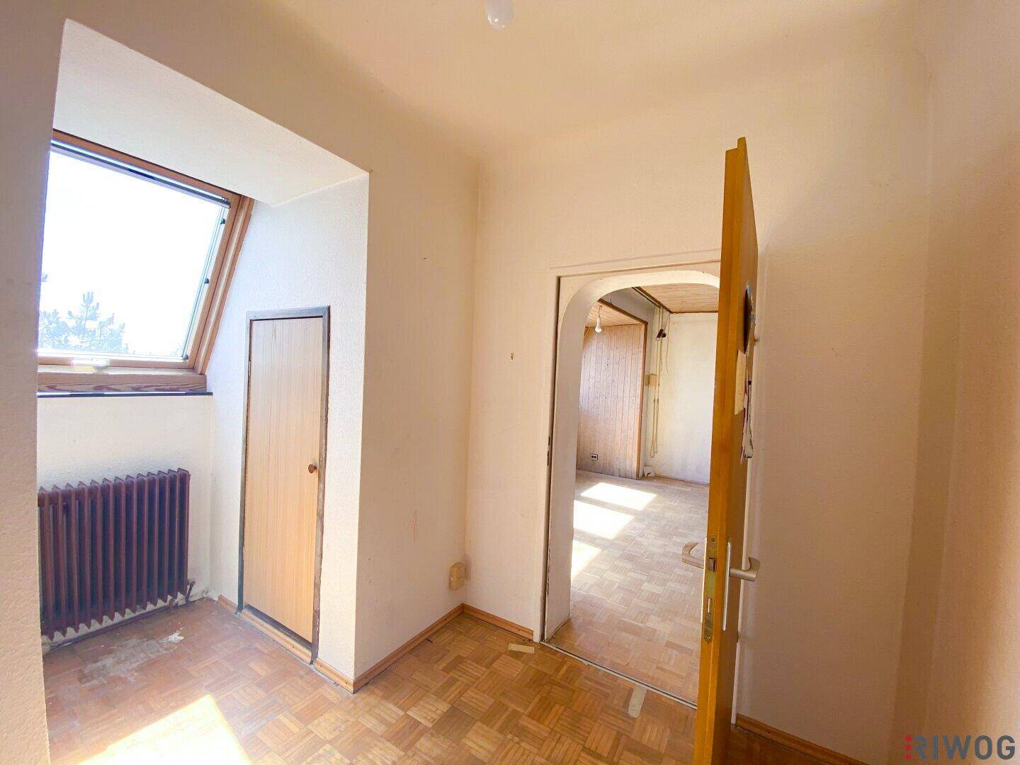 Kleiner Raum mit Dachfenster und Parkettboden, der einen Durchgang zu einem angrenzenden Zimmer bietet.