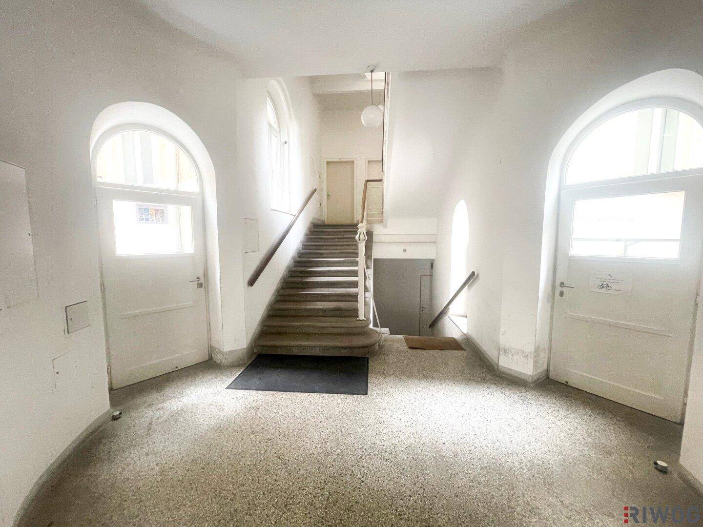 Geräumiges Treppenhaus mit geschwungener Treppe, hohen Decken und natürlichem Lichteinfall.