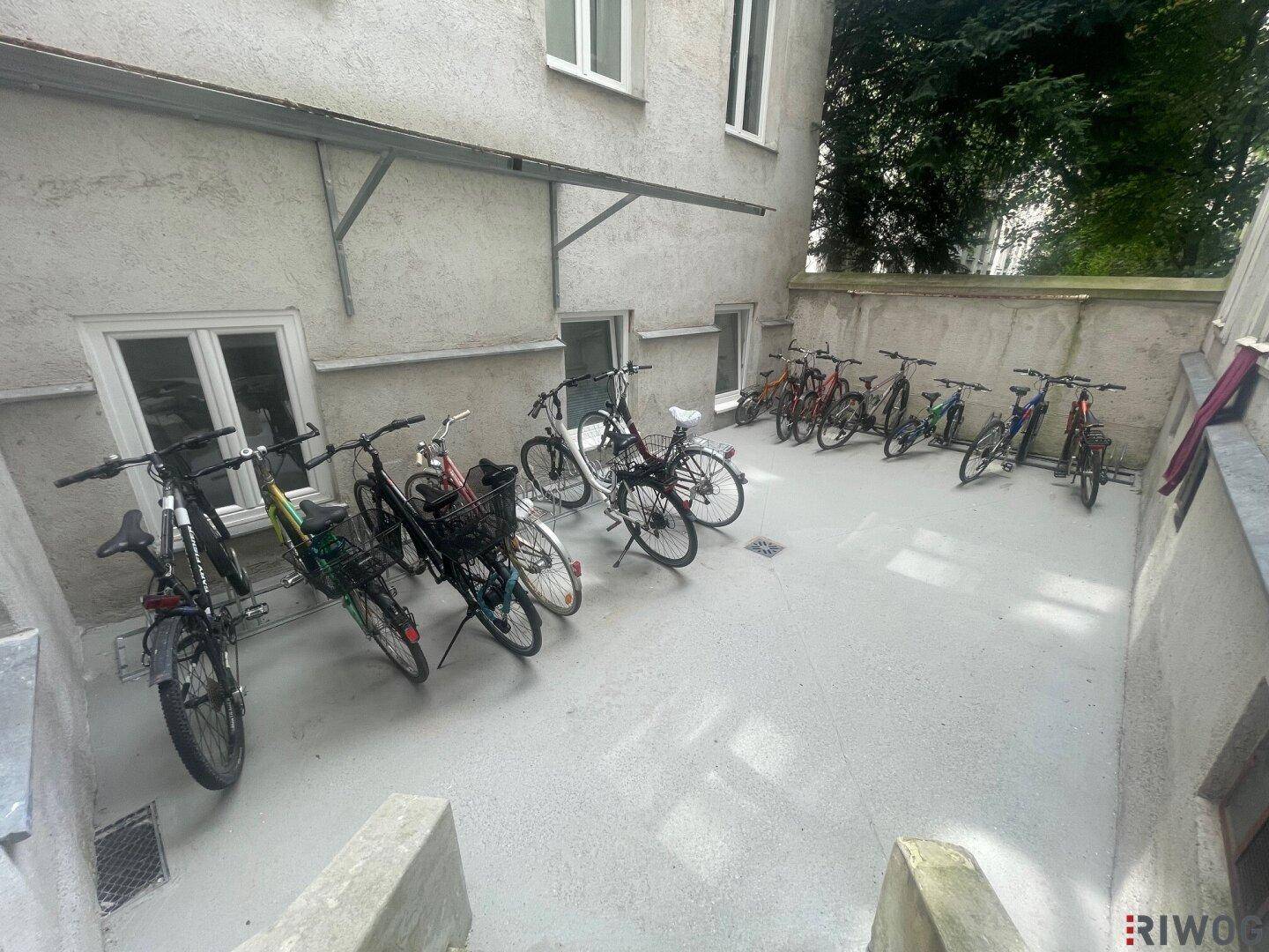 Außenbereich des Gebäudes mit zahlreichen Fahrrädern und einem gepflasterten Boden.