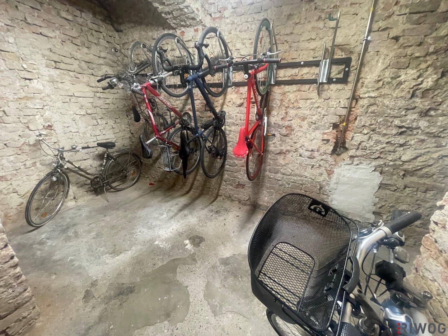 Fahrradabstellraum im Keller mit Ziegelwänden und an der Wand montierten Fahrradhaltern.