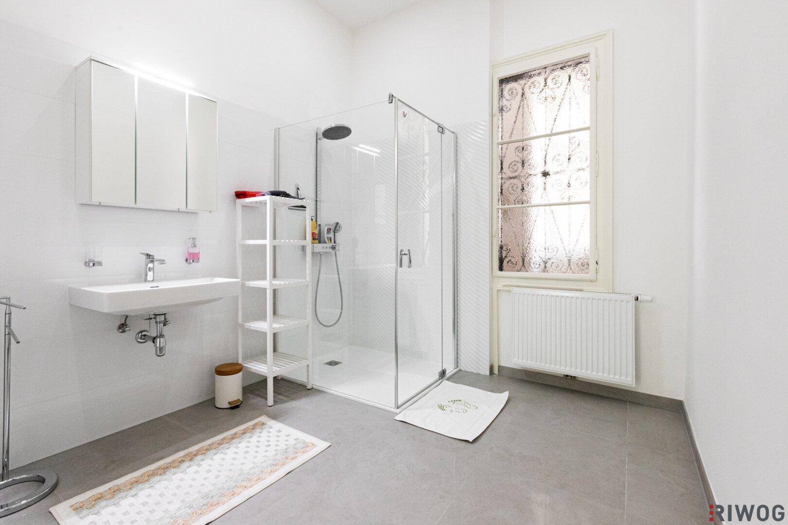 Modernes Badezimmer mit ebenerdiger Dusche, Waschbecken und Fenster.