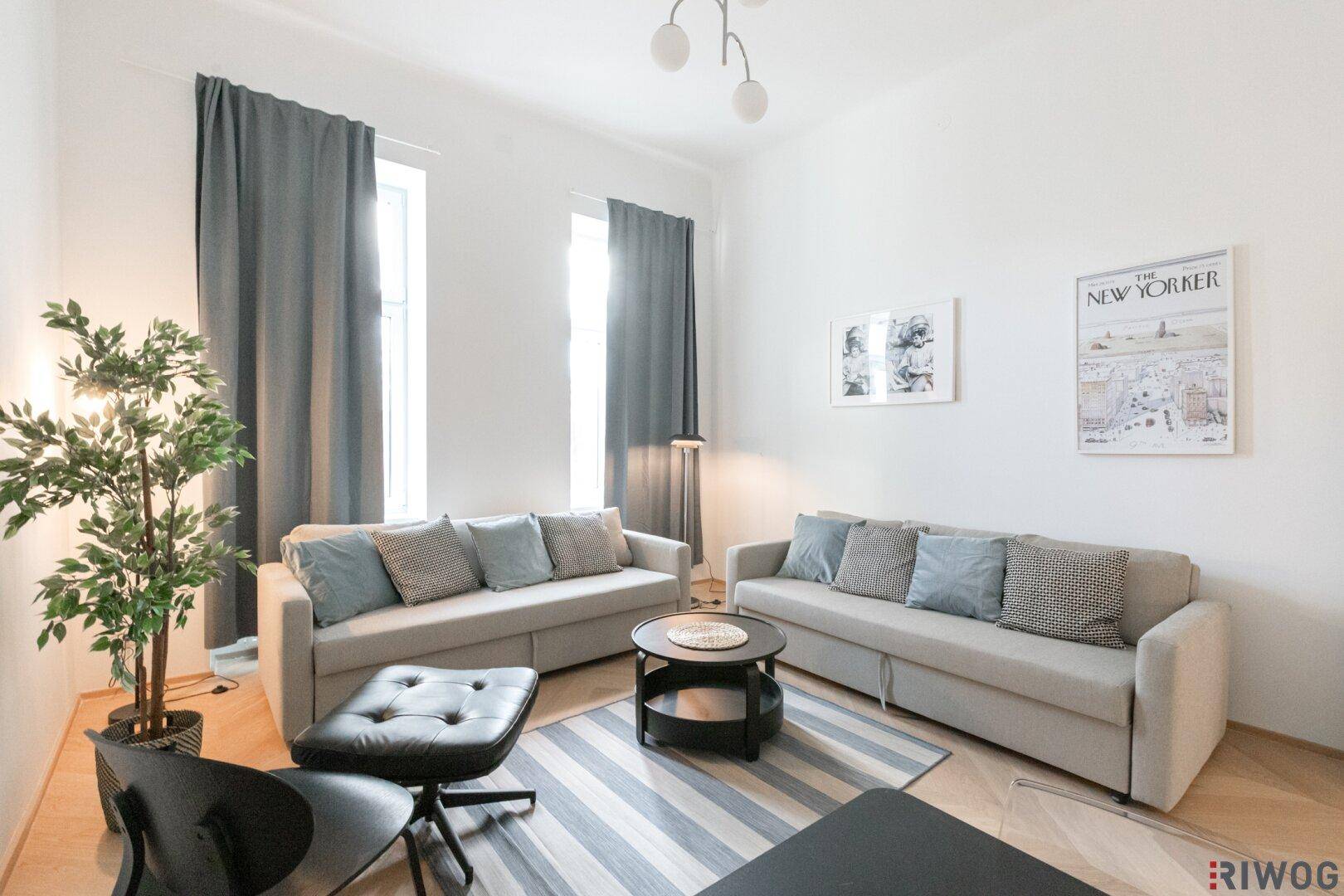 Helles Wohnzimmer mit zwei beigen Sofas, Holzboden und einem runden Couchtisch.