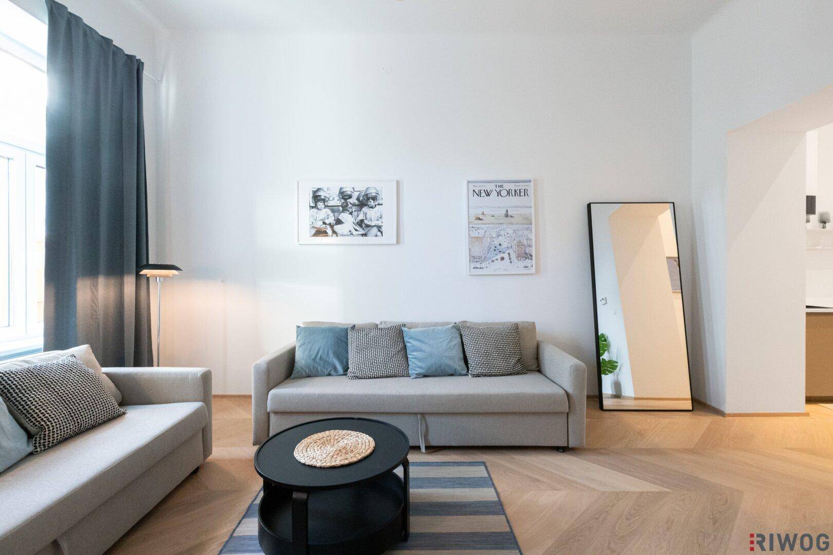 Wohnzimmer mit beigem Sofa, großem Spiegel und modernem Teppich auf Holzboden.