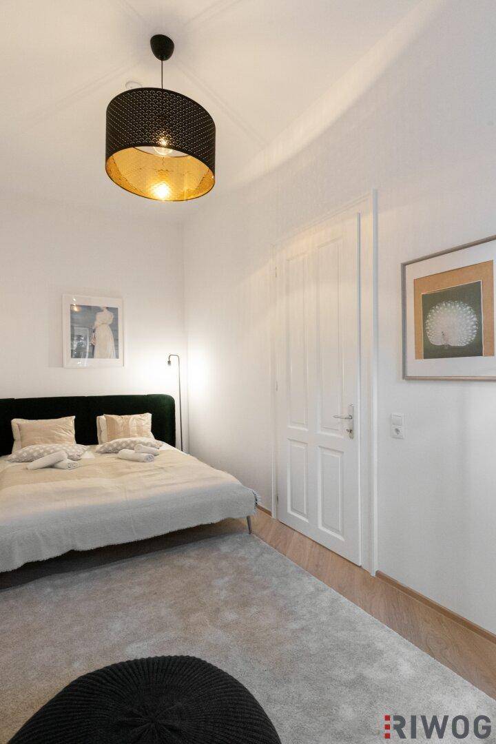 Gemütliches Schlafzimmer mit Doppelbett, Teppich und moderner Deckenleuchte.