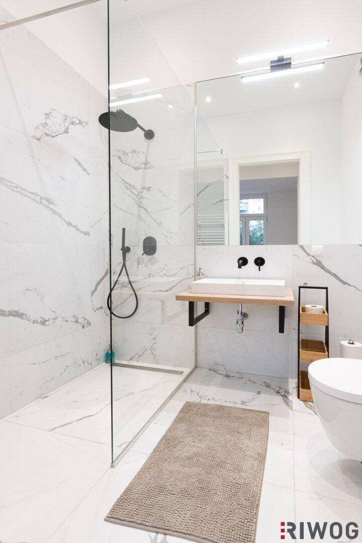 Modernes Badezimmer mit begehbarer Dusche, Marmorfliesen und schwebendem Waschbecken.